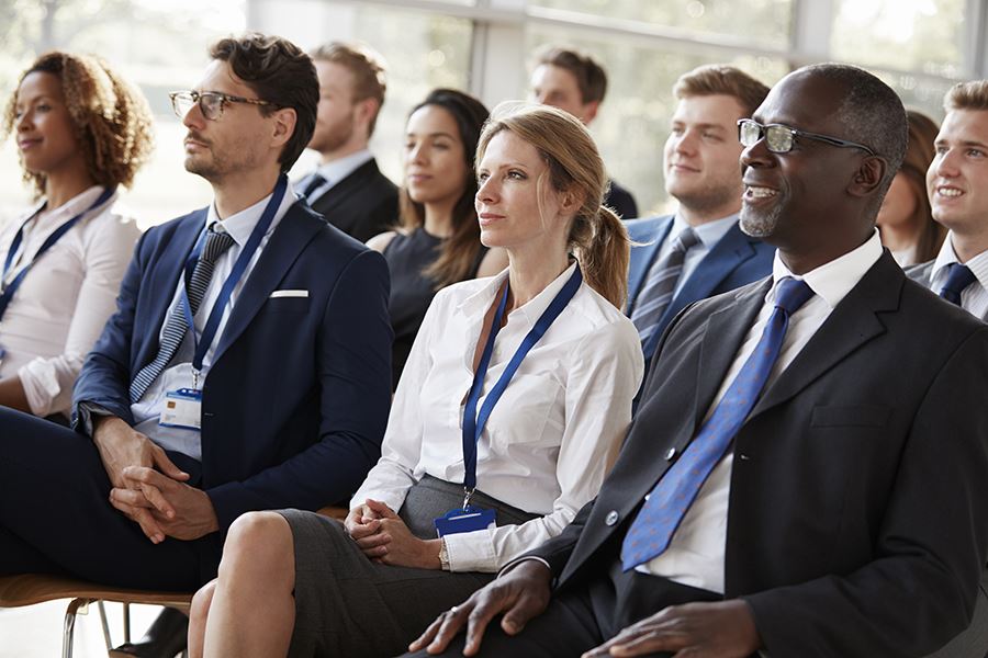 People in business dress in the audience of a presentation.